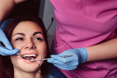 Muayene ile açılan ağız diş hekimleri sandalyede otururken sahip genç bir kadın.