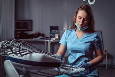 Bir diş kliniğinde onun işyerinde bir sandalyede oturan kadın diş hekimi.