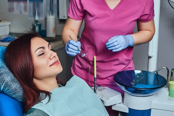 Eine junge rothaarige Frau bei einer Untersuchung, während sie im Zahnarztstuhl in der Klinik sitzt. — Stockfoto