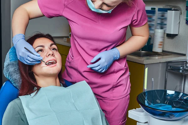 En ung kvinna att ha undersökning medan du sitter i fåtöljen tandläkare med öppnade munnen. — Stockfoto