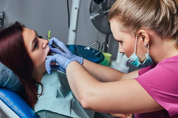 Eine junge Frau bei der Untersuchung, während sie mit geöffnetem Mund im Zahnarztstuhl sitzt. — Stockfoto