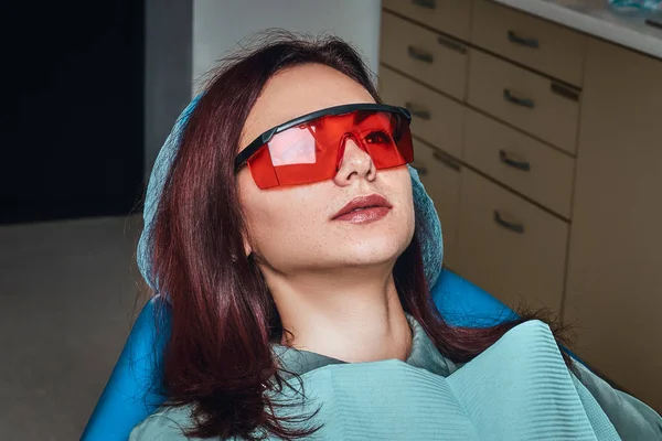 Close-up photo kobiety okularów ochronnych, siedząc w Fotel dentystyczny w klinice. — Zdjęcie stockowe