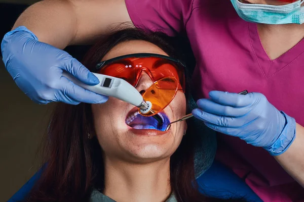 Η θεραπεία ενός ασθενή θηλυκά οδοντίατρο. Μια νεαρή γυναίκα που κάθεται στην πολυθρόνα οδοντιάτρων. — Φωτογραφία Αρχείου