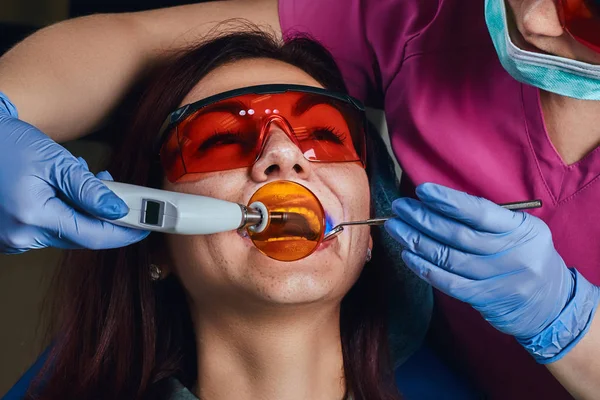 Leczenia pacjenta kobieta dentysty. Młoda kobieta siedzi w fotelu Dentyści. — Zdjęcie stockowe