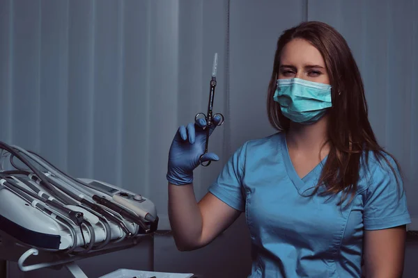 Une dentiste tenant une seringue alors qu'elle était assise dans son cabinet . — Photo
