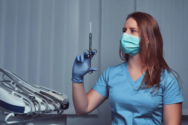 Женщина-дантист держит шприц, сидя в кабинете дантиста . — стоковое фото