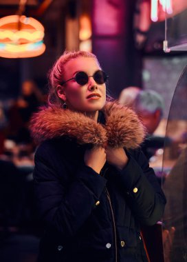 Şehvetli bir kız gece sokakta ayakta. Işıklı tabela, neon, ışıklar.