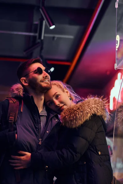 Attractive couple in love. A beautiful girl hugging her boyfriend standing in the night on the street. — Stock Photo, Image