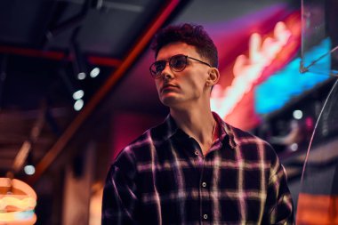 Gece sokakta duran yakışıklı bir genç adam. Işıklı tabela, neon, ışıklar.