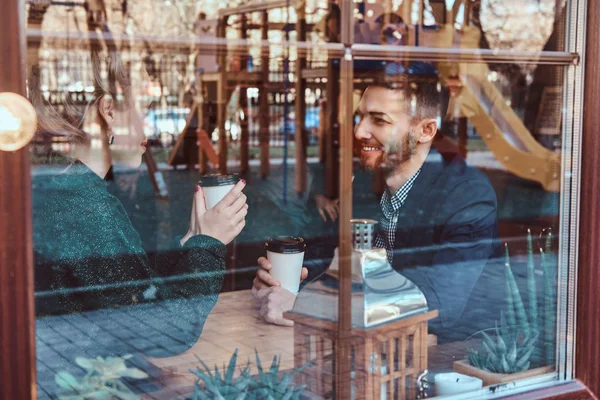 Привлекательная молодая пара смотрит друг на друга и разговаривает, сидя в ресторане за окном . — стоковое фото