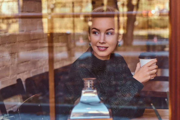 Ein schönes lächelndes Mädchen beim Kaffeetrinken im Café — Stockfoto