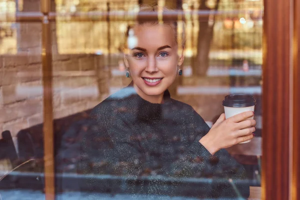 Красивая улыбающаяся девушка пьет кофе в кафе — стоковое фото