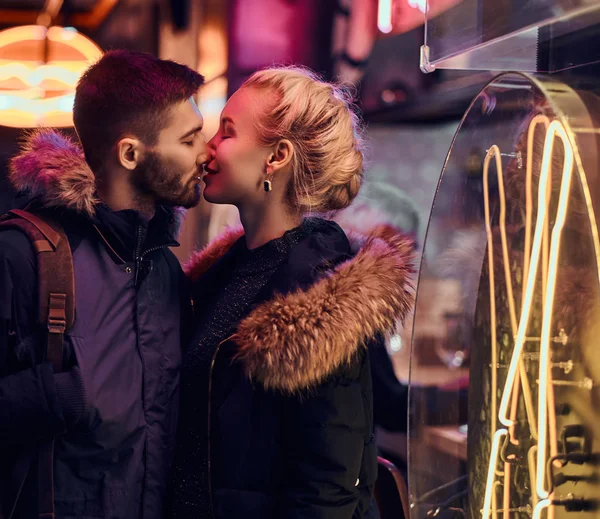Um casal atraente apaixonado. Uma linda garota beija seu namorado de pé na noite na rua . — Fotografia de Stock
