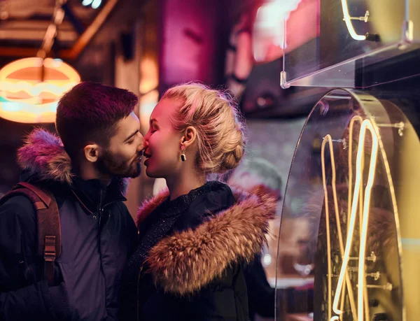 Um casal atraente apaixonado. Uma linda garota beija seu namorado de pé na noite na rua . — Fotografia de Stock