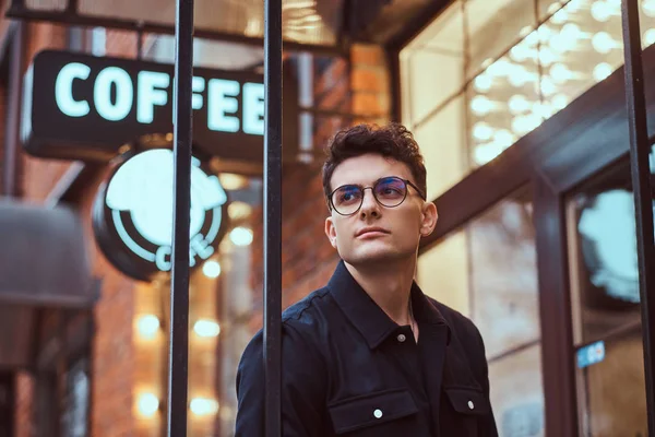 Un joven guapo parado cerca de un café al aire libre . — Foto de Stock