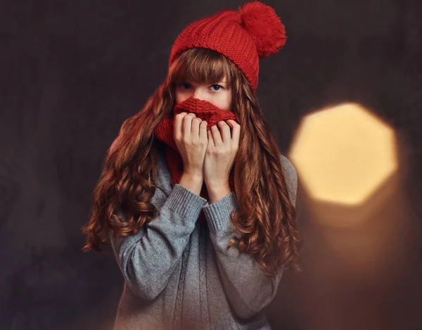 Portrait of a beautiful redhead girl wearing a warm sweater, covers her face with a scarf. — Stock Photo, Image