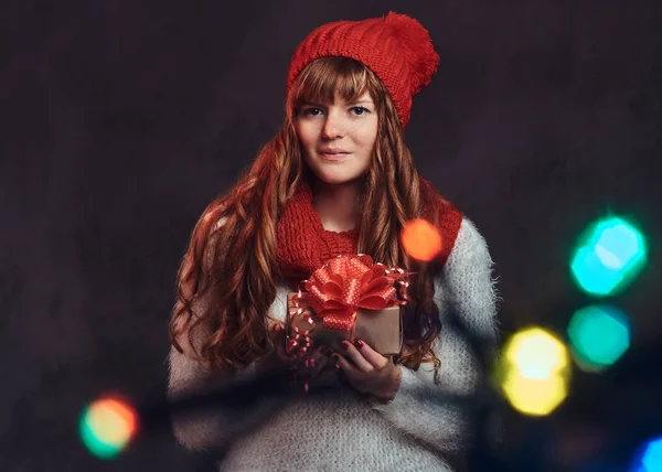 Portrait d'une belle rousse souriante portant un pull chaud et une écharpe tenant une boîte cadeau . — Photo