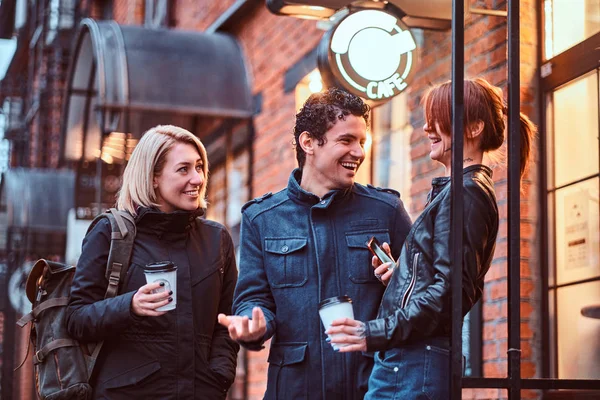 Τρεις φίλους φοιτητές έχοντας ένα διάλειμμα με καφέ κοντά σε ένα καφενείο έξω από. — Φωτογραφία Αρχείου