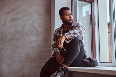 Afrikalı-Amerikalı bir pencere pervazına üzerinde oturan adam sakallı.