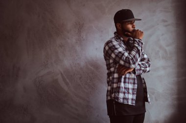 Dalgın Afrikalı-Amerikalı bir gri dokulu duvar yanında duran adam sakallı.