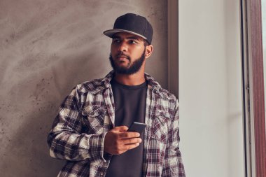 Afrikalı-Amerikalı bir telefon gri dokulu duvar yanında duran adam sakallı.