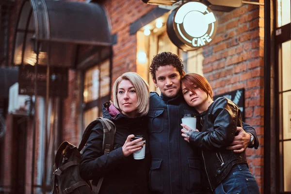 Friends standing together in an embrace near a cafe outside. — Stock Photo, Image