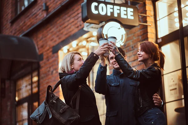 Cheerful friends making a toast with coffee near a cafe outside. — Stock Photo, Image