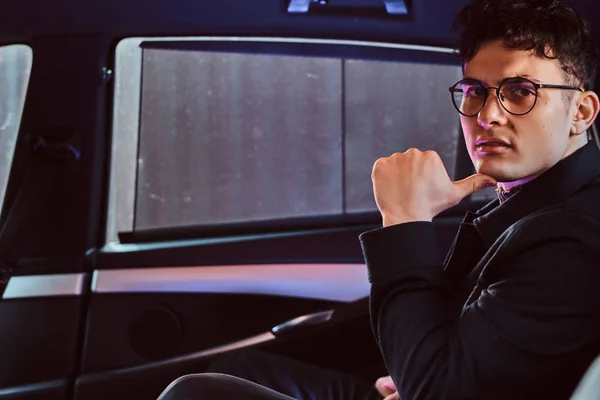 Retrato de un joven hombre de negocios guapo sentado en el asiento trasero del coche de lujo . — Foto de Stock