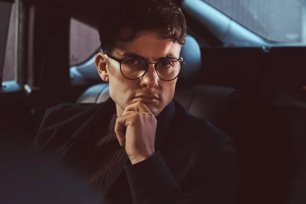 Retrato de un joven hombre de negocios guapo sentado en el asiento trasero del coche de lujo . — Foto de Stock