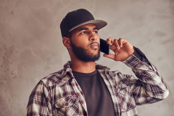 アフリカ系アメリカ人を生やした格子縞のシャツと電話で話しのキャップを身に着けています。 — ストック写真