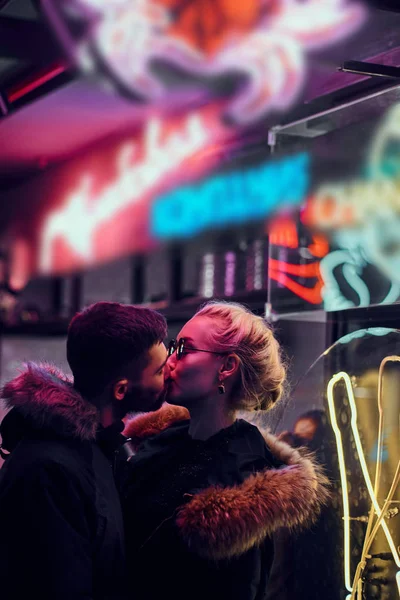 Приваблива пара закоханих. Красива дівчина цілує свого хлопця, що стоїть вночі на вулиці . — стокове фото