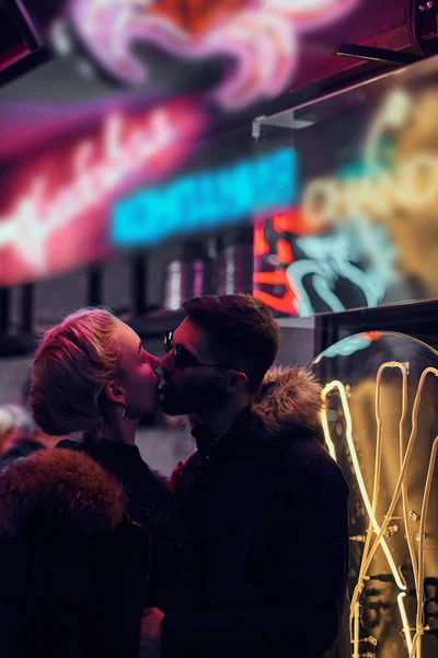 Приваблива пара закоханих. Красива дівчина цілує свого хлопця, що стоїть вночі на вулиці . — стокове фото