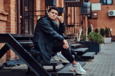 Şık bir adam rahatlatıcı ve merdivenlerde otururken müzik.