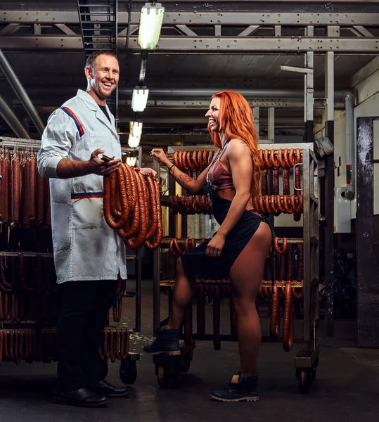 Butcher and his sexy girl assistant in the storage room. — Stock Photo, Image