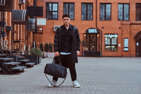 Een trendy jonge man gekleed poseren en camera kijken op straat. — Stockfoto