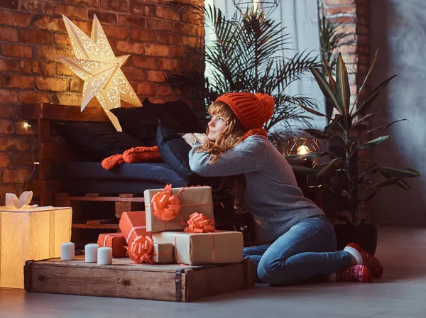 Redhead girl sitting on a floor dreamily looks out the window in a decorated living room at Christmas time. — Stock Photo, Image