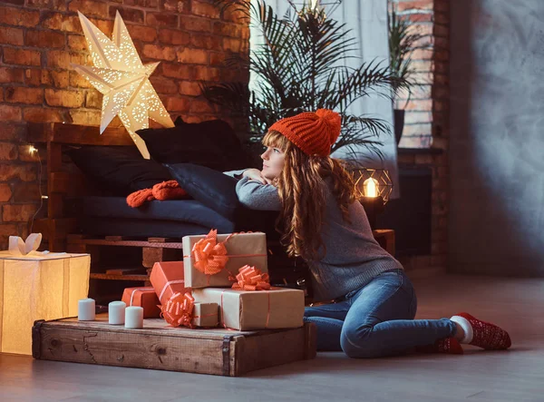 Redhead girl sitting on a floor dreamily looks out the window in a decorated living room at Christmas time. — Stock Photo, Image