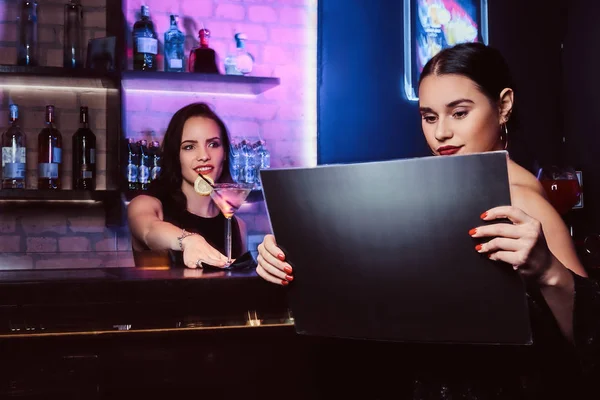 Krásná dívka sedí u baru čítače a čtení menu v nočním klubu — Stock fotografie
