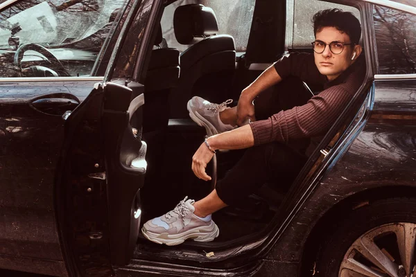 Красивий молодий чоловік тримає смартфон, розслабляючись на задньому сидінні розкішного автомобіля . — стокове фото