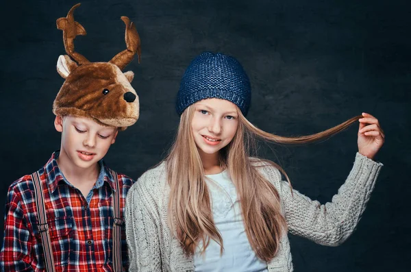 Porträtt av en leende flicka i vintermössa och söt pojke i rådjur hatt. — Stockfoto