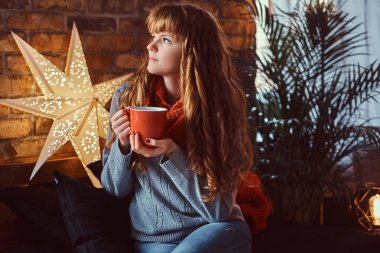 Bir fincan kahve bir şekilde dekore edilmiş salon ile Noel zamanda ısınma Kızıl saçlı kız.
