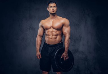 Atletik yakışıklı kaslı vücut bir halter disk tutarak ve uzağa arıyorsunuz