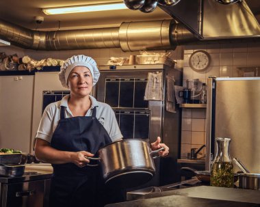 Bir pan Restoranlar mutfak tutan bir üniforma giyen bir orta yaş aşçı. 