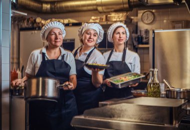 Pişirme kapları doğranmış sebze, restoranlar mutfak at bir kamera için poz ile tutarak bir üniforma giyen takım.