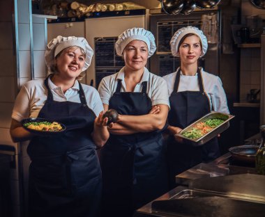 Pişirme kapları doğranmış sebze, restoranlar mutfak at bir kamera için poz ile tutarak bir üniforma giyen takım.
