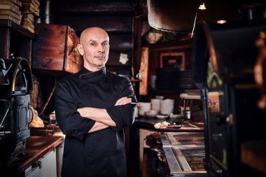 Kendine güvenen Şef geçti ve lokanta mutfağı kamera bakarak kolları poz.