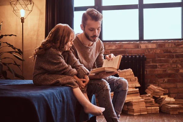 Bonito pai lê seus contos de fadas filha enquanto eles sentados na cama . — Fotografia de Stock