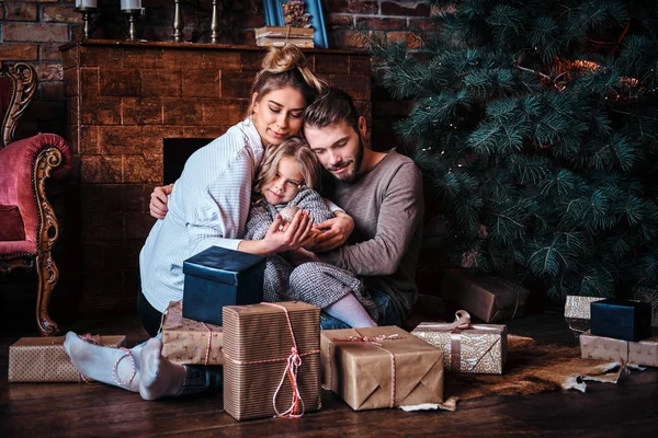 Hediyeler, şömine ve Noel ağacı yanında ailesiyle birlikte bir yere oturmak sevimli küçük kız çevrili mutluluk — Stok fotoğraf