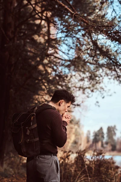 Un joven excursionista con suéter calienta las manos en el frío bosque otoñal . — Foto de Stock