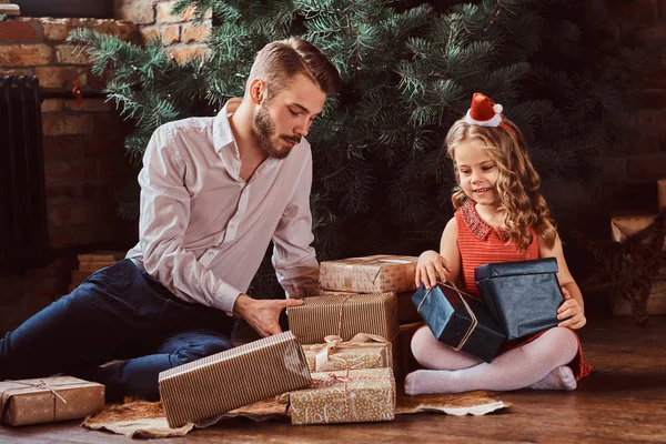 Папа и дочь сидят на полу в окружении подарков рядом с елкой дома . — стоковое фото